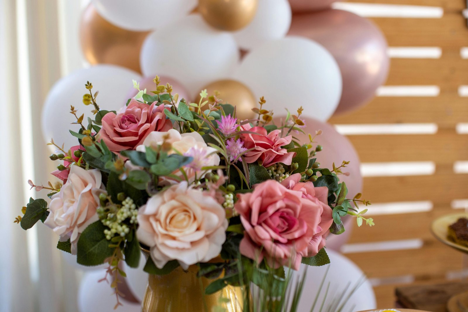 A stunning floral arrangement with pink roses and balloons, ideal for celebrations.